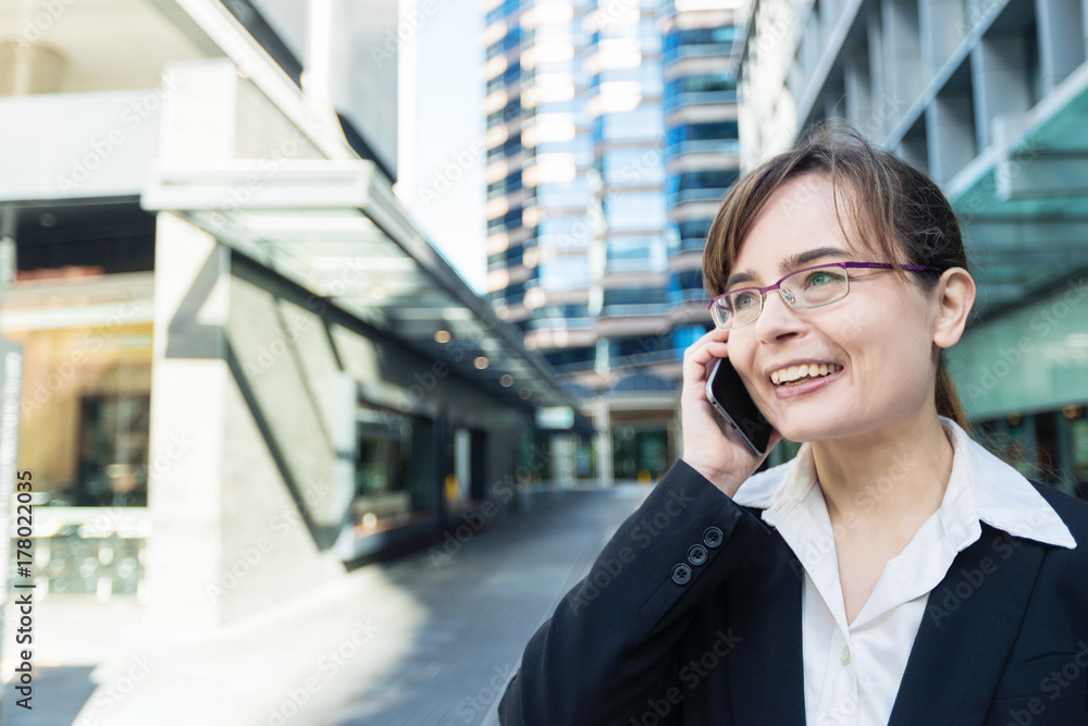 Portrait of business woman in glasses in the city talking on the phone and smiling Portrait of business woman in glasses in the city talking on the phone and smiling