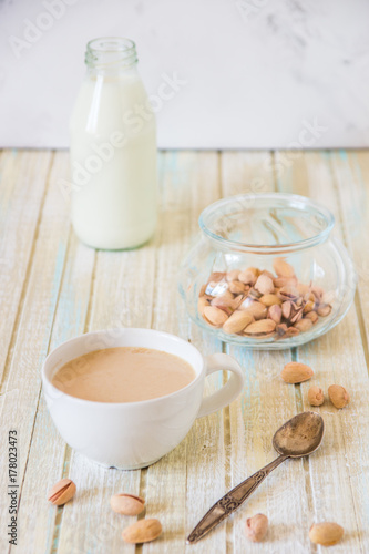 Coffee with milk and pistachios on wooden table