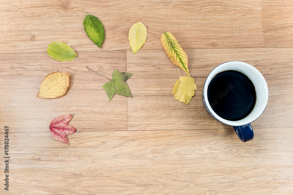 Autumn background with a cup of warming coffee, that stands on a wooden table and decorated with autumn leaves Autumn background with a cup of warming coffee, that stands on a wooden table and decorated with autumn leaves