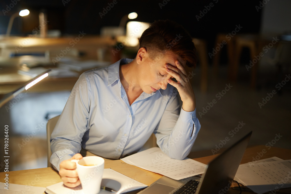 Mature economist napping by workplace in dark office late in the evening