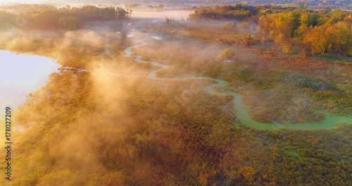 Aerial view of breathtaking foggy wilderness at dawn, with winding river, Autumn colors. photo
