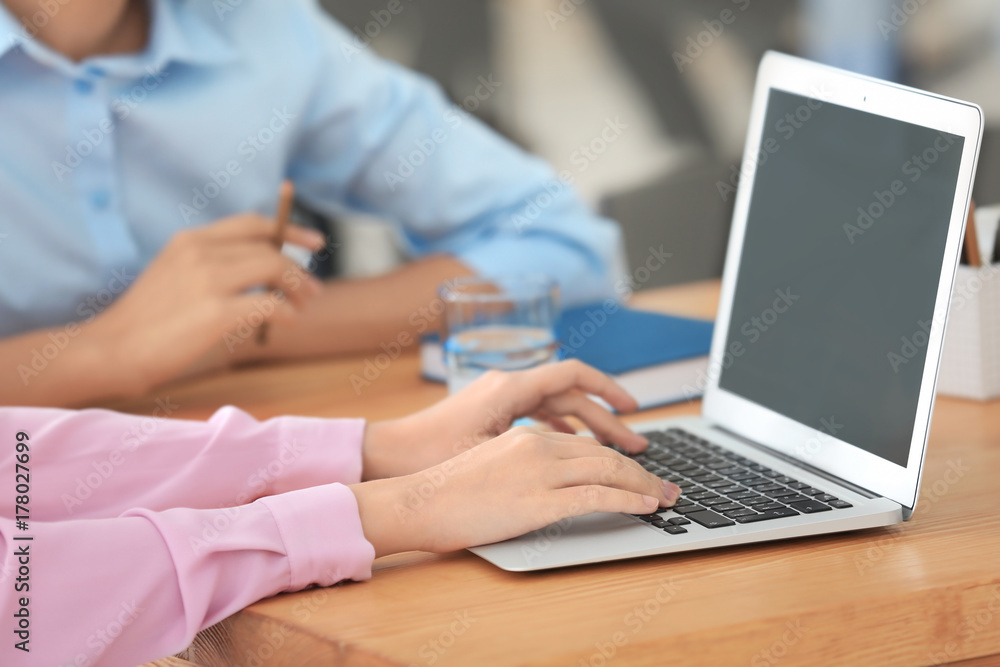 Fototapeta premium Young woman using laptop on table in office