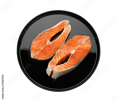 Plate with fresh salmon steaks on white background