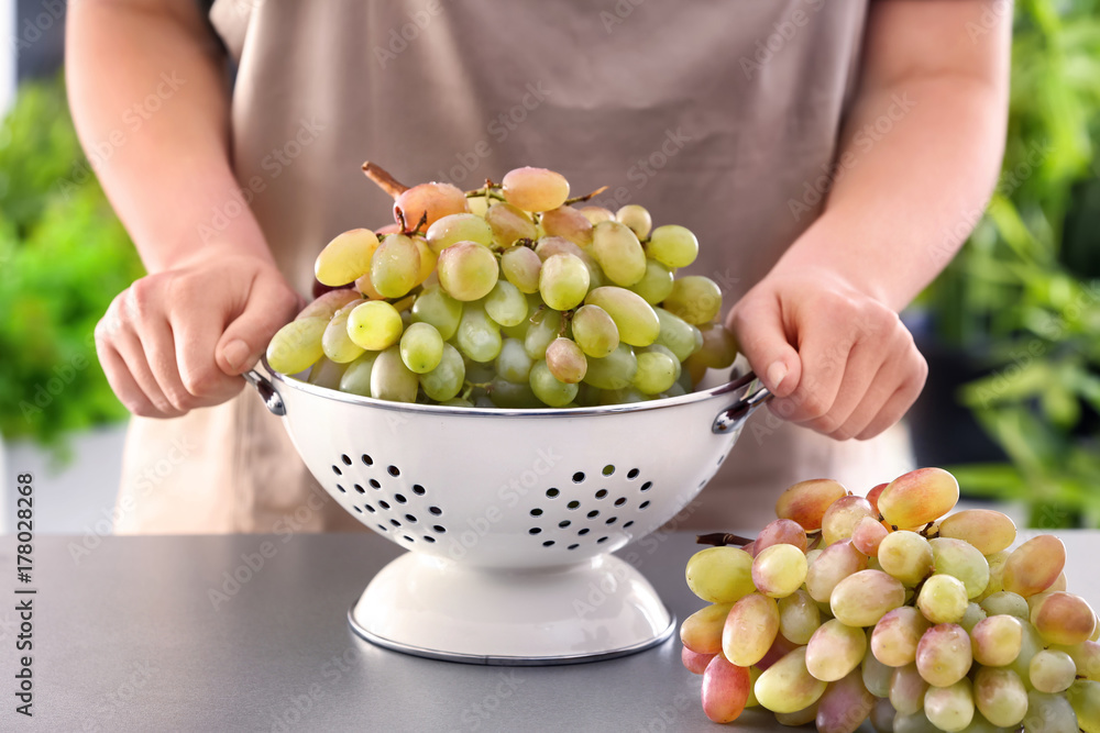 Fototapeta premium Woman with fresh ripe grapes on table outdoors