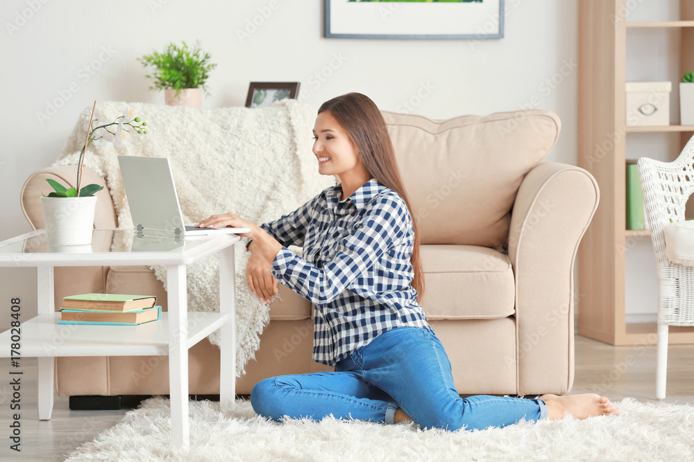 Pretty woman with modern laptop sitting on carpet at home Pretty woman with modern laptop sitting on carpet at home