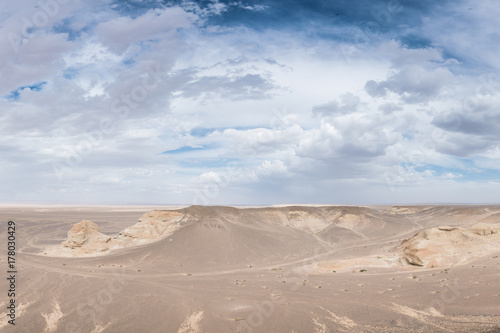 beautiful sunlit white desert with fluffy clouds on blue sky 