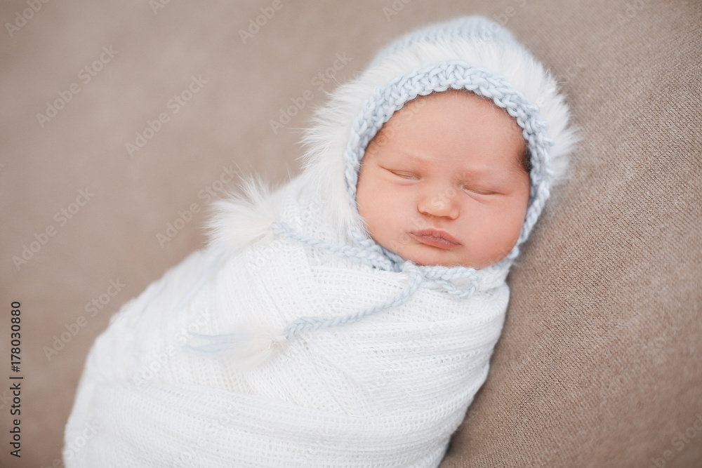 Sleeping newborn baby girl in a gently blue knit hat. Sleeping on a covered sheet.
