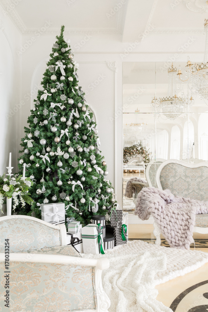 Fototapeta premium Christmas morning. classic apartments with a white fireplace, decorated tree, bright sofa, large windows