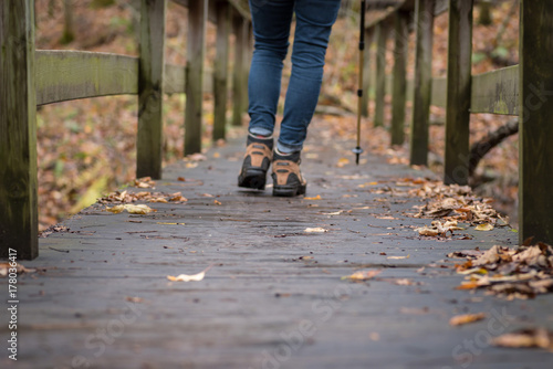 woman walking across wooden bridge in forest in fall