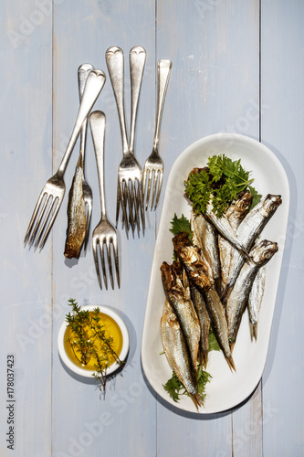 sprats and parsley on a plate, a small bowl with olive oil and thyme