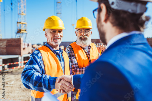 Construction worker and businessman shaking hands