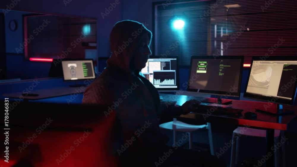 Computer hacker surrounded by screens tries to gain access to computer system Computer hacker surrounded by screens tries to gain access to computer system