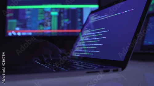 Male hacker working on a computer in a dark office room.