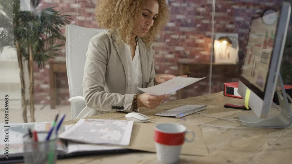 Businesswoman in modern office working on computer & checking financial data Businesswoman in modern office working on computer & checking financial data
