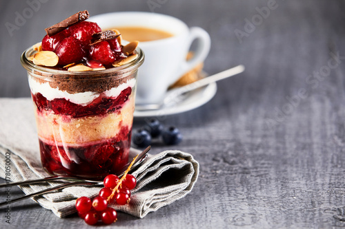 Layered fruit dessert in jar with cup of coffee