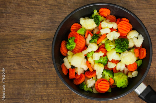 Mixed vegetables. cauliflower, broccoli and carrots in an iron pan on a wooden background. with copy space. top view