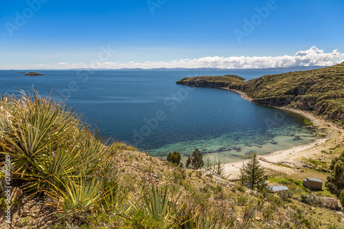 Blue water and coast of Titicaca lake, boats, walking people and bolivian village at Incas Island of the Sun, Bolivia, south America