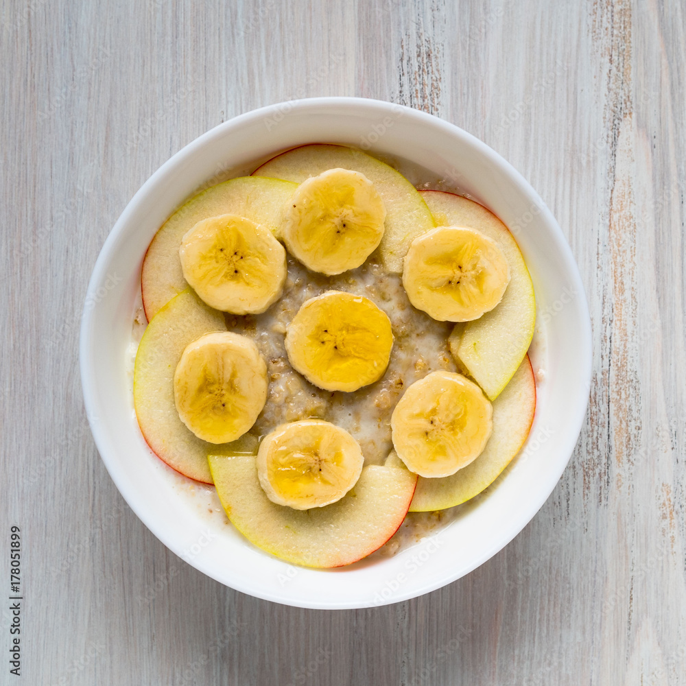 Healthy Breakfast in the morning - oatmeal with fruit and honey, slices of apples and bananas, caramel syrup. Top view. Healthy Breakfast in the morning - oatmeal with fruit and honey, slices of apples and bananas, caramel syrup. Top view.