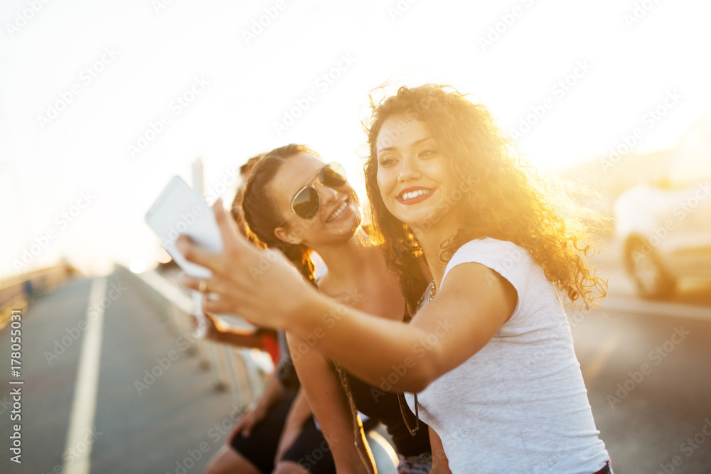 Two playful smiling girls taking a selfie in the city.
