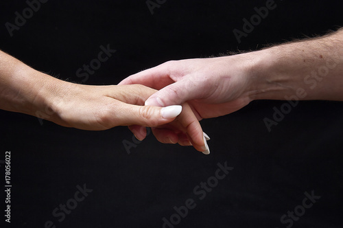 Male and female hands together on black background