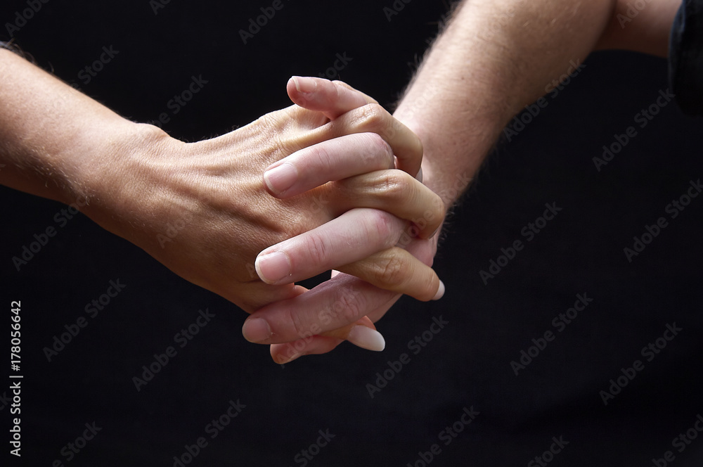 Male and female hands together on black background