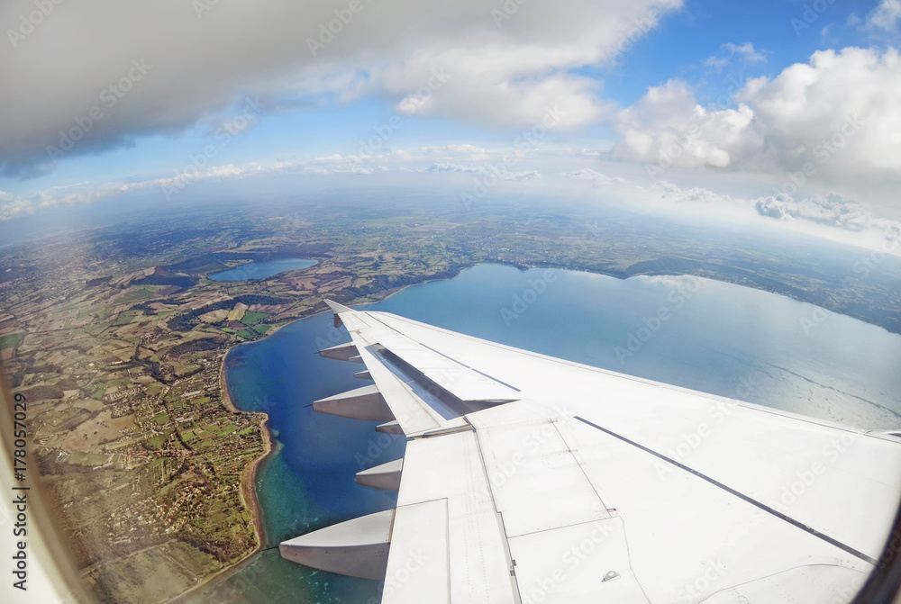 Passenger airplane in flight .View from airplane window on fields ,sea , clouds on the sea coast , Italy Passenger airplane in flight .View from airplane window on fields ,sea , clouds on the sea coast , Italy