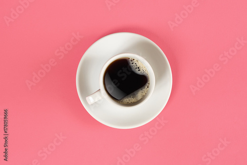 A cup of black coffee on pink background. View from above.