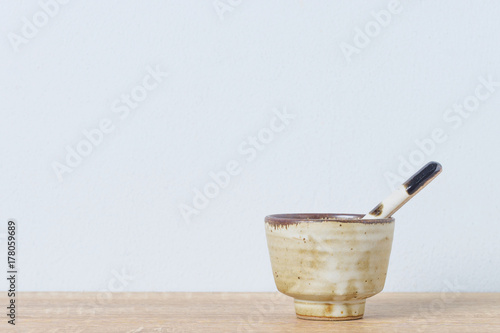 Ceramic bowl and ceramic spoon on wooden table