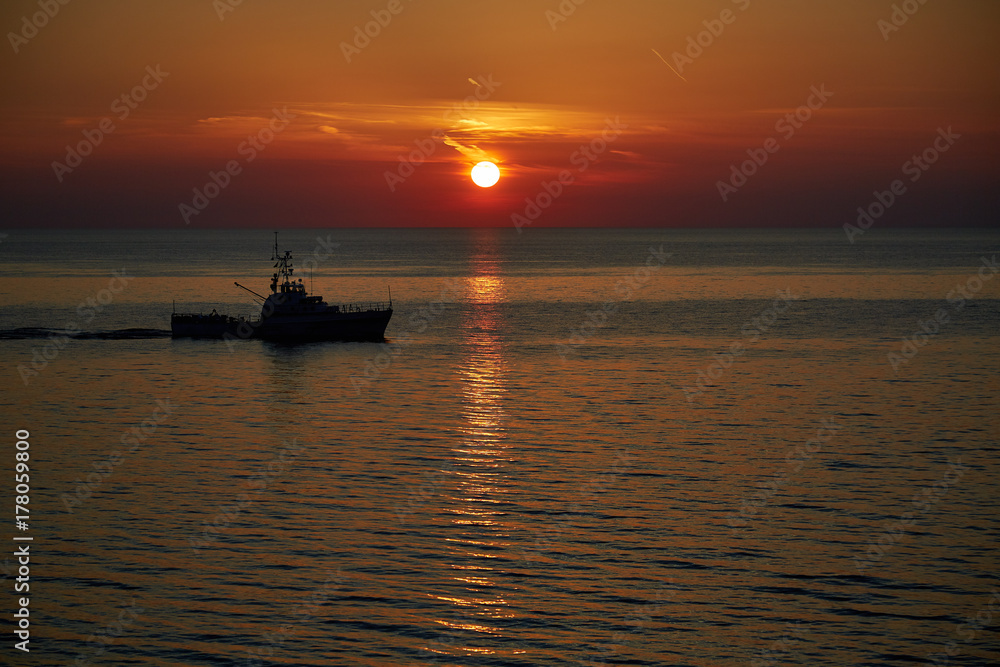 silhouette of a patrol boat on the sea at sunset