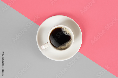 A cup of black coffee on gray and pink background. View from above.