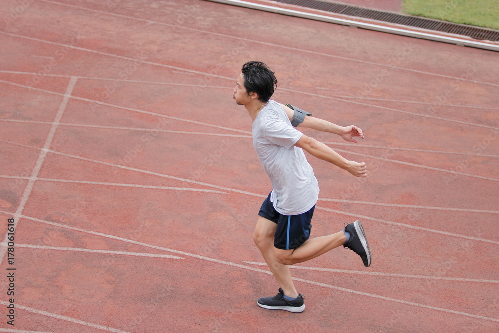 Athletic handsome young Asian runner sprinter crossing the finish line on track in stadium. Athletic handsome young Asian runner sprinter crossing the finish line on track in stadium.