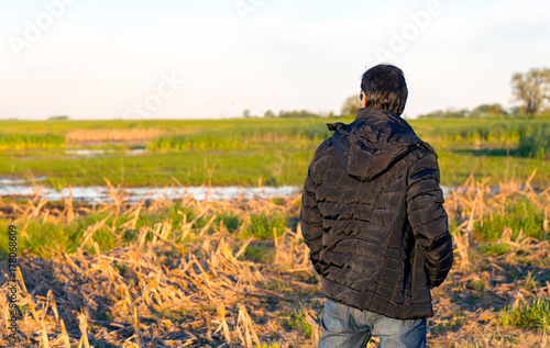 Man in the middle of a field looking at the corn fields. © AlexPhotoStock
