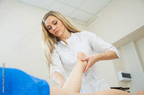 Beautician masseuse massaging female legs, bodycare concept