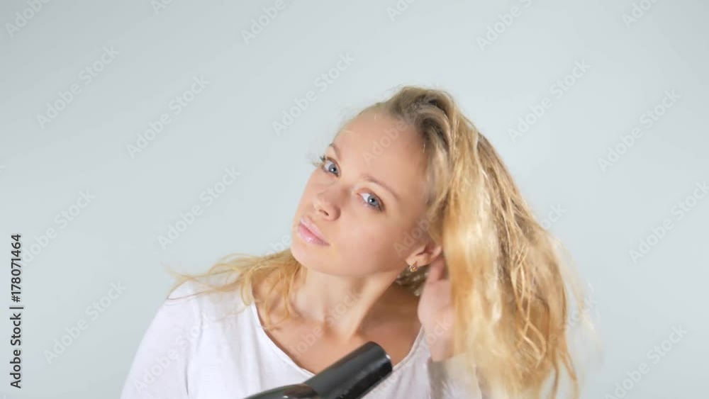 4k. Blonde dries hair a Hairdryer . Isolated on white background. 4k. Blonde dries hair a Hairdryer . Isolated on white background.