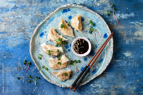 Asian dumplings with soy sauce, sesame seeds and microgreens. Traditional chinese dim sum dumplings. Copy space, flat lay