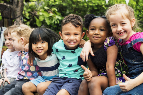 Group of kindergarten kids friends arm around sitting and smiling fun