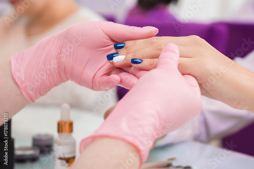 A manicurist takes care of the client s hands. Close up photo in beauty salon