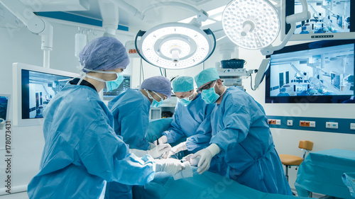 Fotografie, Obraz Medical Team Performing Surgical Operation in Bright Modern Operating Room
