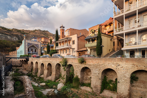 View of the Bath Street in the Abanotubani district in the center of Tbilisi. River on the background of Georgian houses with traditional wooden balconies. City landscape.