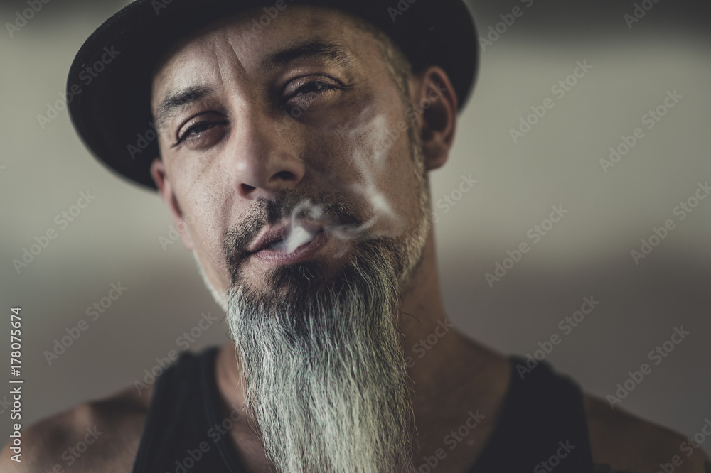 Rugged man with tattoos smokes and gesticulates Rugged man with tattoos smokes and gesticulates