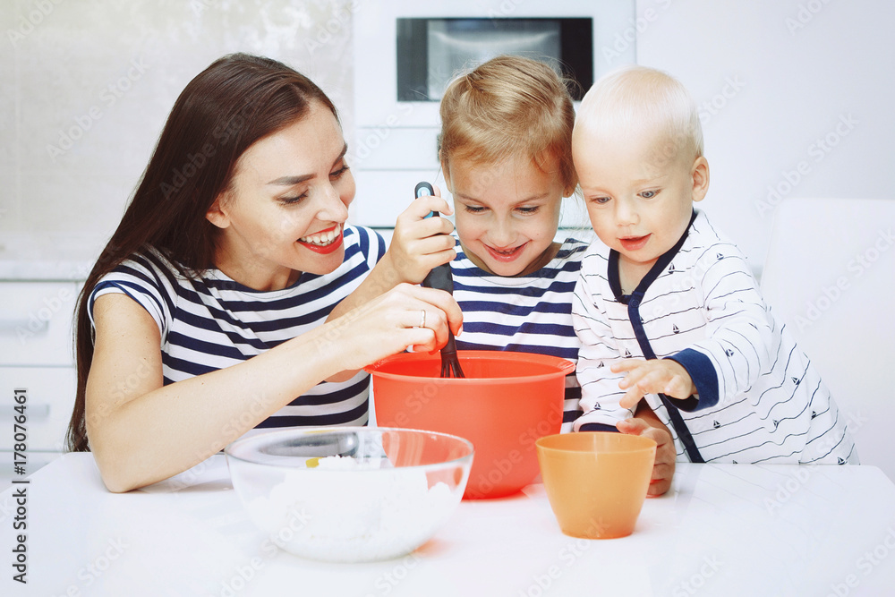 Adorable happy family makes cakes together on your white kitchen. Adorable happy family makes cakes together on your white kitchen.