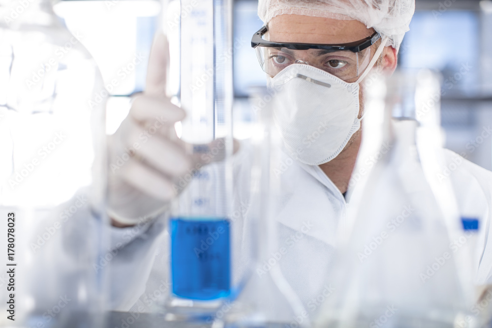 Scientist working in lab holding a cylinder Scientist working in lab holding a cylinder