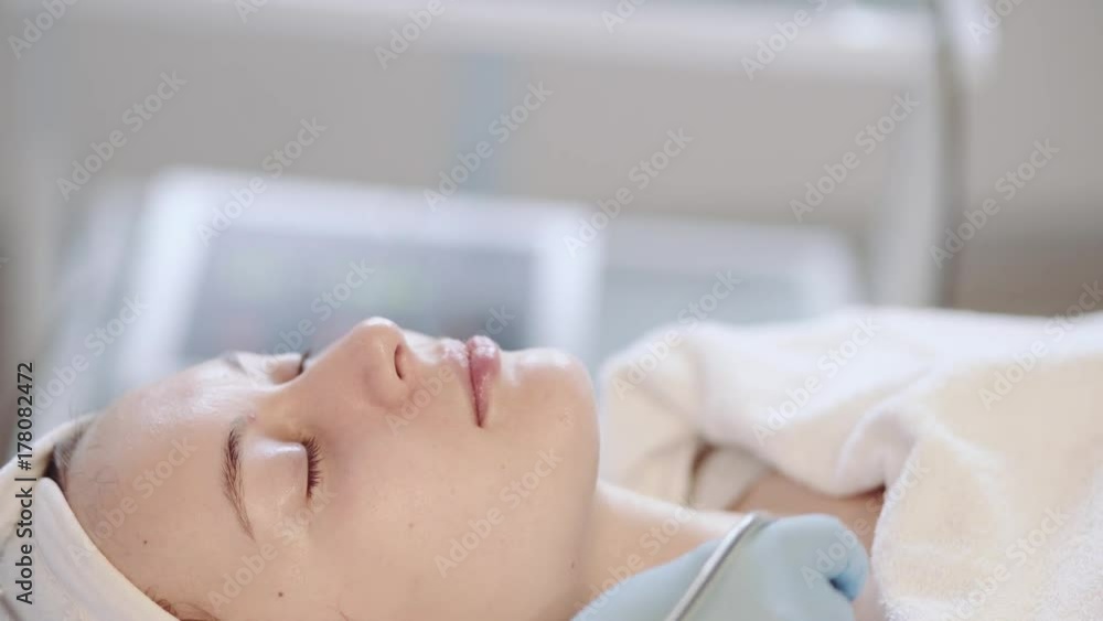 Young Woman getting a cosmetic medicine spa treatment, close up. 4K UHD, Slow Motion. Beautician hands at work, providing led light skin treatment therapy to a girl face. Special beauty equipment. Young Woman getting a cosmetic medicine spa treatment, close up. 4K UHD, Slow Motion. Beautician hands at work, providing led light skin treatment therapy to a girl face. Special beauty equipment.
