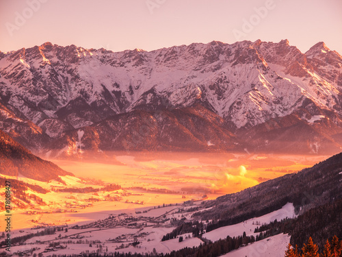 Panoramic view of winter mountains. Alpine peaks and valley in morning fog.