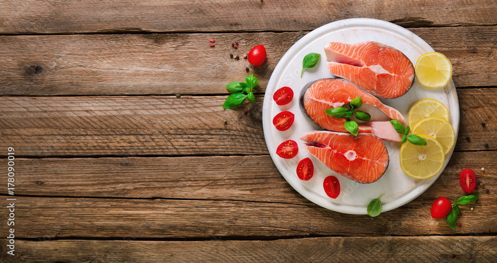 Salmon steaks with lemon, herbs, spices cherry tomatoes on wooden background. Healthy diet food concept. Top view. Copy space Salmon steaks with lemon, herbs, spices cherry tomatoes on wooden background. Healthy diet food concept. Top view. Copy space