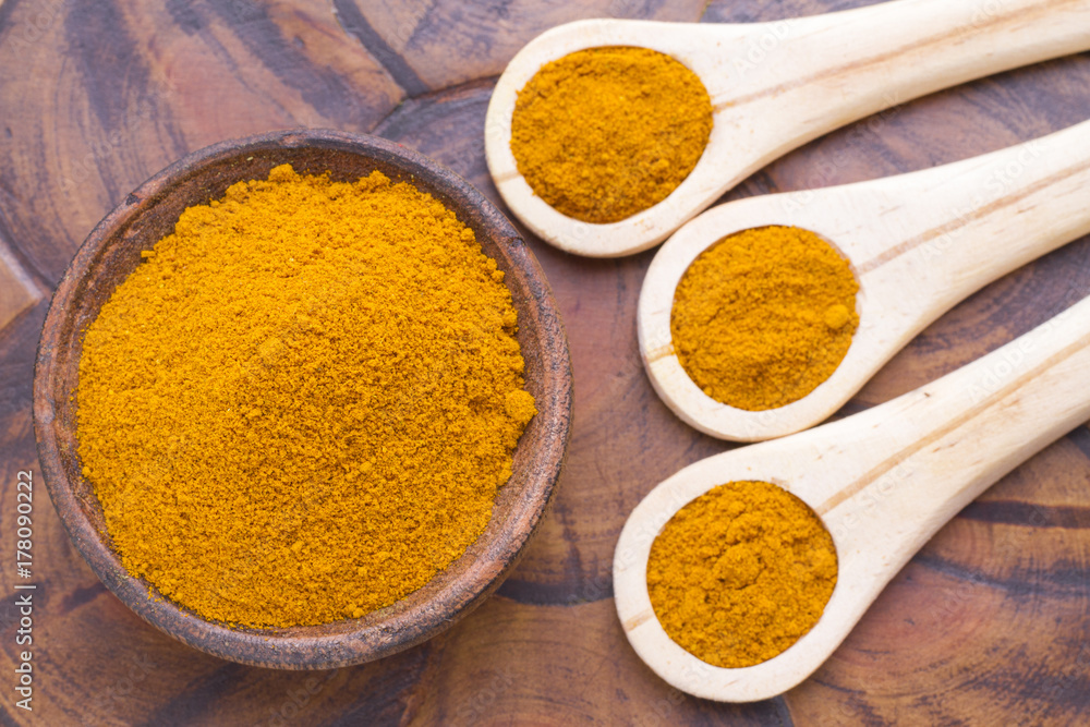 Turmeric powder with spoon on wood background (curcuma longa) Turmeric powder with spoon on wood background (curcuma longa)