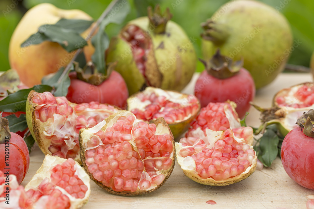 Autumn fruits with green background. pomegranate, apple, persimmon.