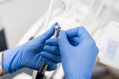 Dentist's hands with blue gloves configure dental drill in dental office. Close-up