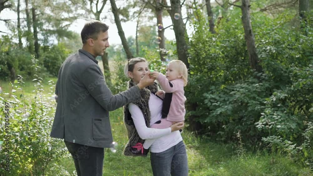Happy family rest on the nature with kid, blowing and catching bubbles Happy family rest on the nature with kid, blowing and catching bubbles