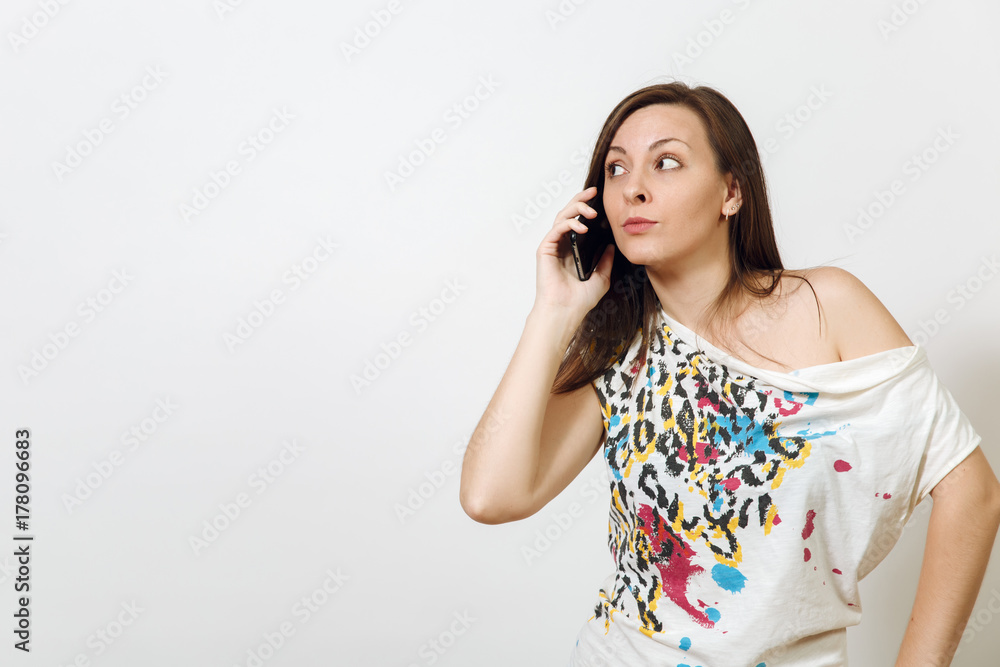 Beautiful perplexed serious brown-haired woman talking on mobile phone on white background. Emotions concept. Beautiful perplexed serious brown-haired woman talking on mobile phone on white background. Emotions concept.